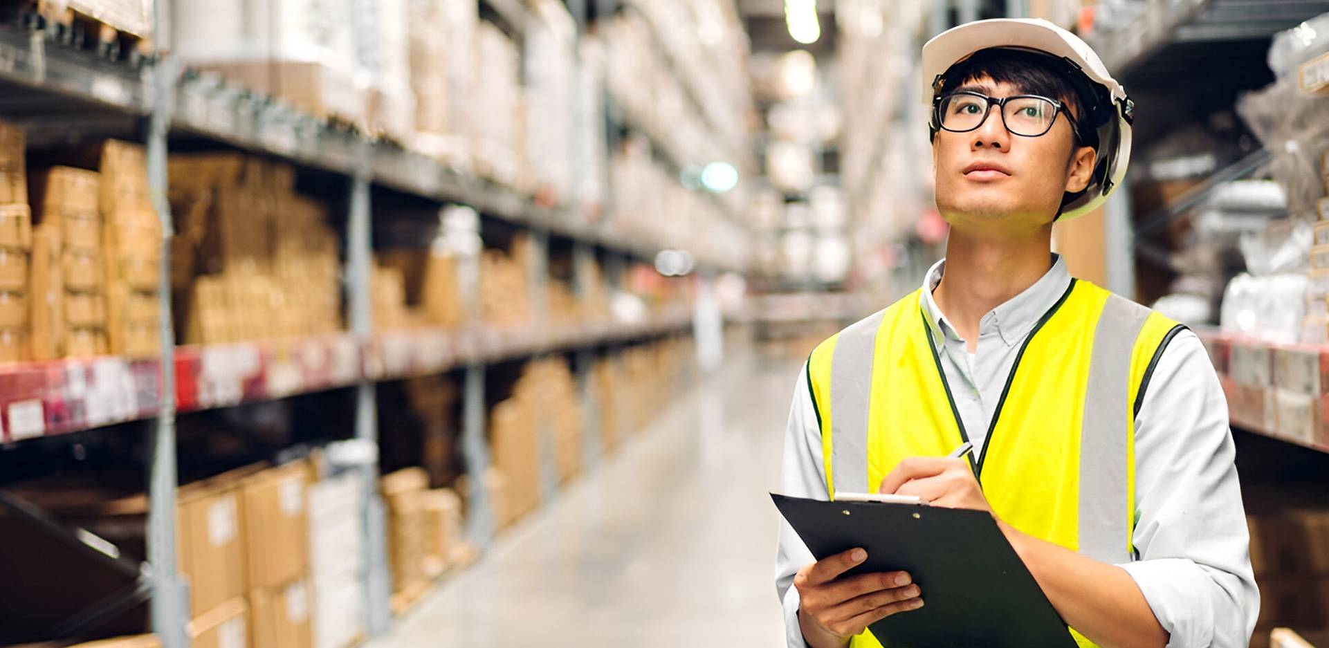 A man with notepad and pen in his hands standing in a warehouse